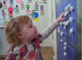Toddler playing with cotton balls at school